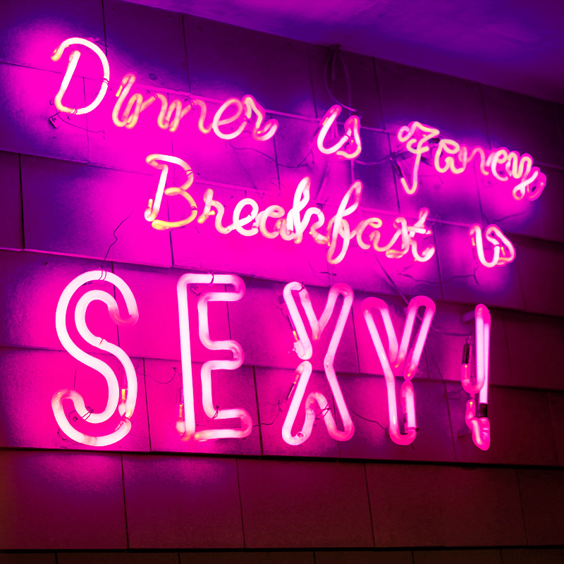 neon sign with the words Dinner is Fancy, Breakfast is SEXY
